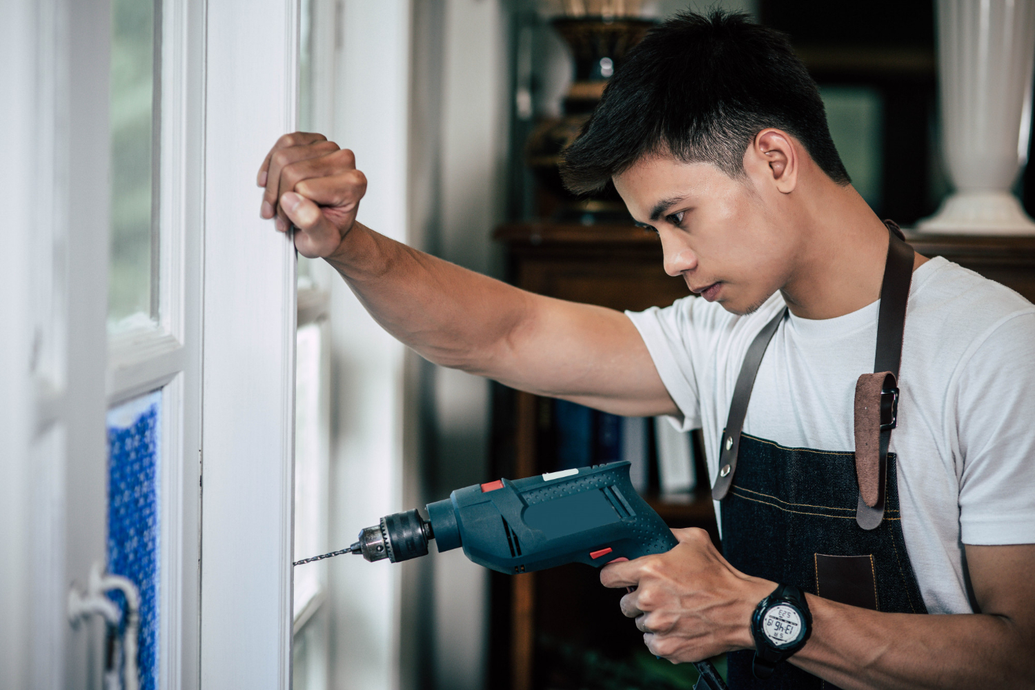 Free photo the carpenter holds the drill and drills the window.<br />
